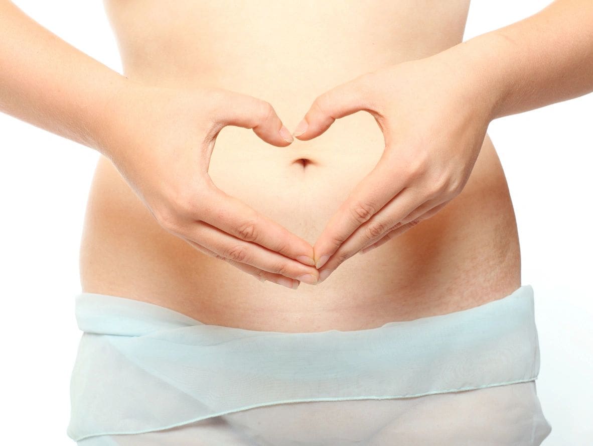 Hands forming heart over pregnant belly.