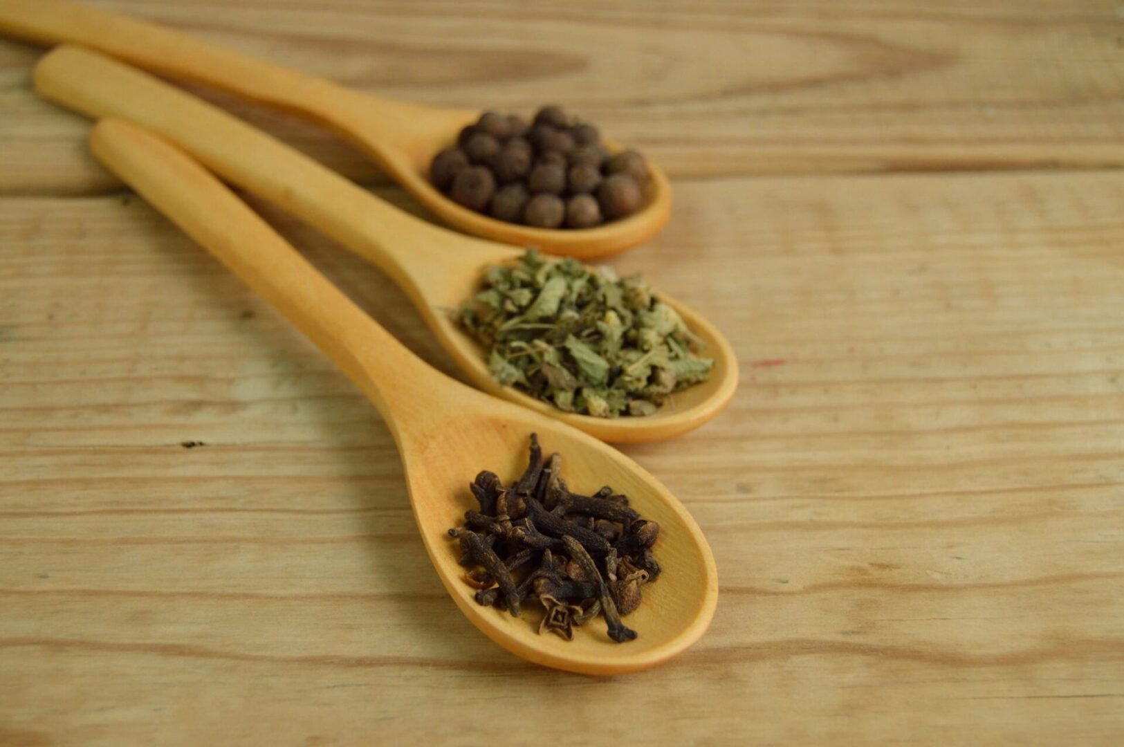 Wooden spoons with assorted spices on table.